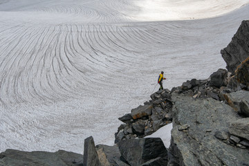 A mountain climber climb down the mountain pass on the background of glacier.