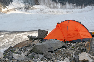Orange tent on the background of glacier.