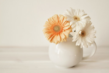 Ceramic vase with gerbera flowers on white wall background. Spring postcard on Mothers Day with flowers. Greeting card template.