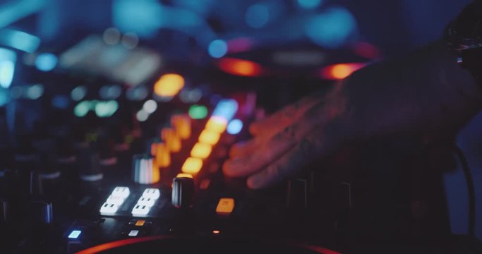 Closeup hands of man DJ play music on mixing console in the night club - slow motion video