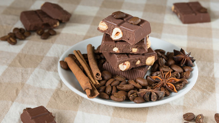 still life, installation, a plate with chocolate, coffee beans, anise and cinnamon sticks on a table