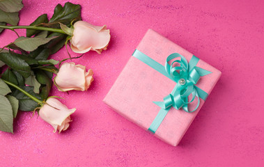 A gift for the holiday in the form of flowers and boxes in pink paper on a pink background.