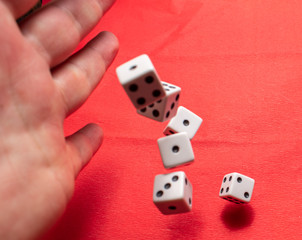 Hand throwing dice, hoping for the best odds. Six dice on red background