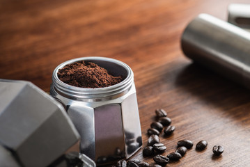 ground coffee in Moka pot and on wooden table preparing coffee to brew.