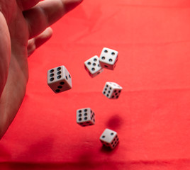 Hand throwing dice, hoping for the best odds. Six dice on red background