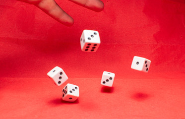 Hand throwing dice, hoping for the best odds. Six dice on red background