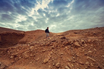 Human hiking in a desert. Desert landscape with dramatic cloudy sky