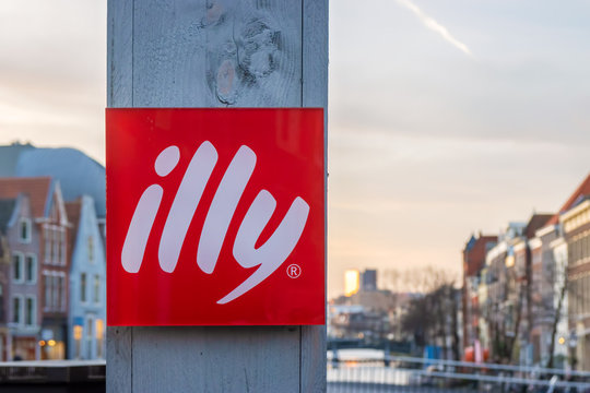 Illy coffee logo on a wooden pole in front of a canal during sunset in Leiden, The Netherlands on January 16, 2020