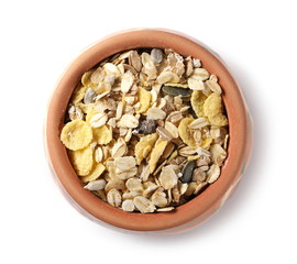 Muesli mixture of wholegrain foods, cereals, seeds and raisins in clay bowl isolated on white background, top view