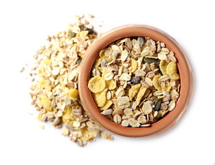Muesli mixture of wholegrain foods, cereals, seeds and raisins in clay bowl isolated on white background, top view