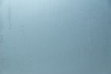 backdrop of ice on a frozen window covered with frost into blue abstract background