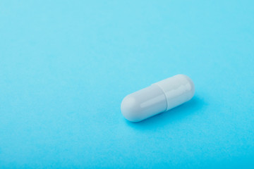White capsules medications or supplements on a colored background