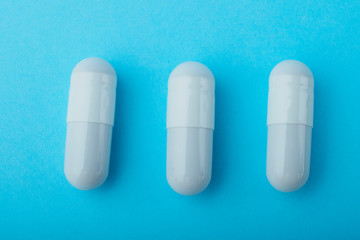 White capsules medications or supplements on a colored background