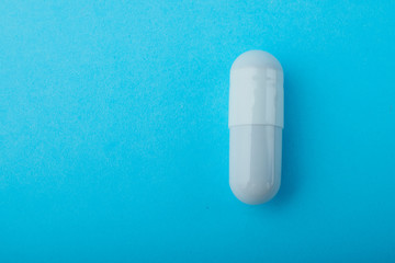 White capsules medications or supplements on a colored background