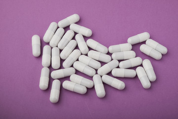 White capsules medications or supplements on a colored background