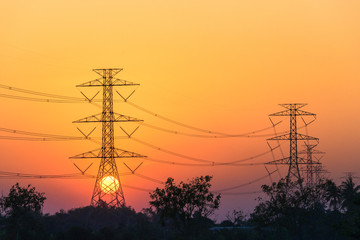 Sunset with high tension electric poles on the middle of paddy fields in the evening.
