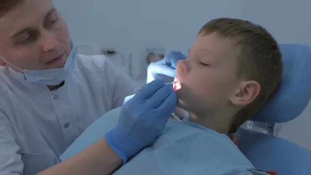 Dentist making fluoridation of child boy teeth after cleaning for protection. Doctor hygienist applying fluoride to teen teeth with brush. Covering teeth with fluoride gel in dentistry. Cure concept.