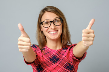 Happy caucasian female wearing red gress making thumb up sign