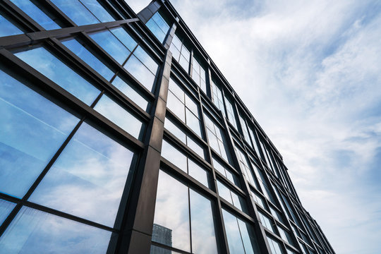 Fototapeta Clouds reflected in windows of modern office building