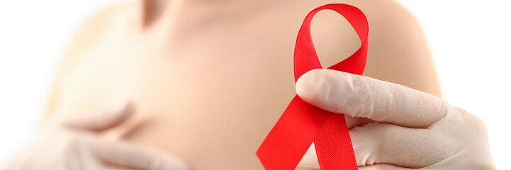 Female hand in gloves holding red ribbon cancer symbol breast closeup on doctor mammology clinic...