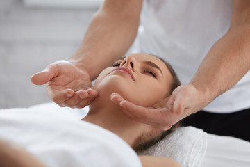 Fototapeta na wymiar Young beautiful woman enjoying anti-aging facial massage.Male therapist making head massage to female client.Professional masseur.Relaxation,beauty,spa,body and face treatment concept.