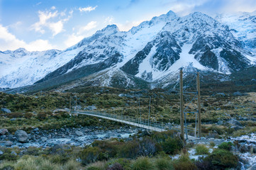 Hiking in moutnains landscape with suspension bridge and snow covered mountains