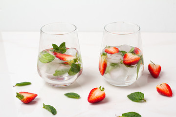 two glasses with a drink with strawberries and fresh mint on a white background