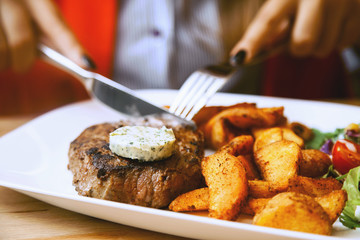 Young woman eating grilled steak in restaurant