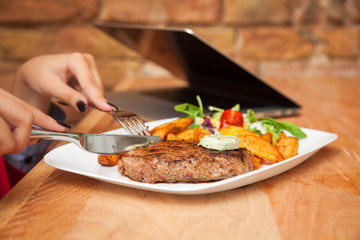 Young woman eating grilled steak in restaurant