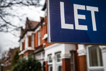 Estate agency 'Let' sign board on street of red brick houses