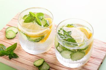 Healthy refreshing summer cocktail or mocktail without alcohol with lemon and cucumber. Summer detox drink on fresh green background, healthy living, top view