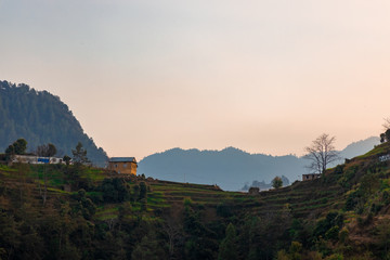 A traditional Nepali house in a village on hill during sunset.