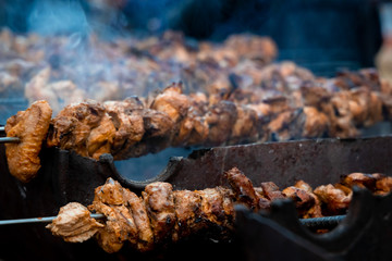 Outdoor Barbecue. Man cooking meat on barbecue grill for his friends. Group of friends enjoying barbecue outdoor.