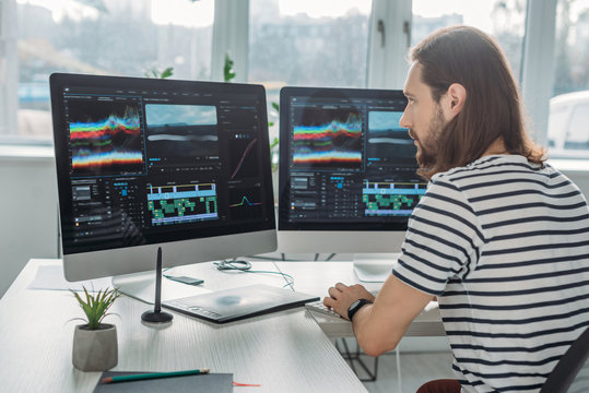 handsome editor sitting and working near computer monitors