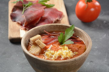 Traditional Spanish andalusian tomato cream soup Salmorejo served with egg, ham jamon, bread in woooden bowl. Summer cold soup concept
