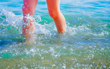 Summer holiday concept. Close up of children's feet in sea water. Selective focus.