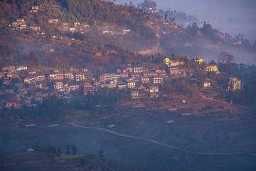 Fototapeta premium Traditional Nepali village in the mountains covered in fog during sunrise