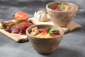Traditional Spanish andalusian tomato cream soup Salmorejo served with egg, ham jamon, bread in woooden bowl. Summer cold soup concept