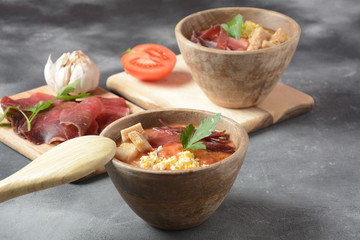 Traditional Spanish andalusian tomato cream soup Salmorejo served with egg, ham jamon, bread in woooden bowl. Summer cold soup concept