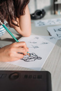 cropped view of illustrator drawing storyboard on paper