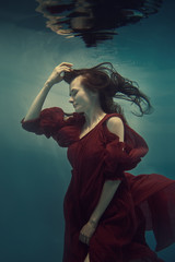 Portrait of a girl in a red dress under water