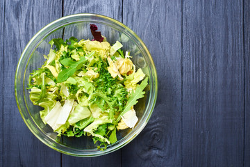 Vegetarian salad mix of fresh vegetables on a dark wooden background. Healthy and wholesome organic...