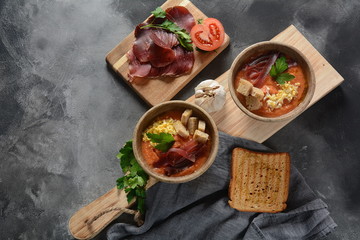 Traditional Spanish andalusian tomato cream soup Salmorejo served with egg, ham jamon, bread in woooden bowl. Summer cold soup concept
