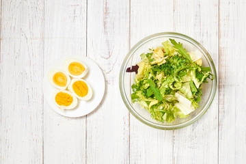 Vegetarian salad mix of fresh vegetables and boiled chicken eggs on a white wooden background. Healthy and wholesome organic food, diet, proper nutrition concept.