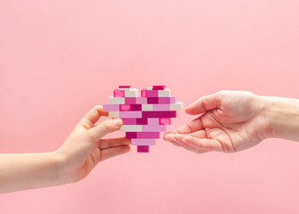 Child's love for mom. A child gives mom a heart made of blocks. Mothers Day or Valentines day concept. 