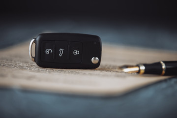 Black car key and money on a signed contract