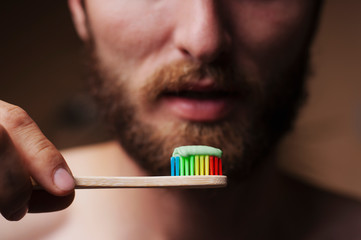 Bearded man brushing his teeth and looking into the camera.Bamboo toothbrush.Close-up.