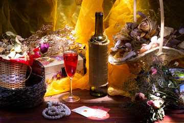 still life with a bottle of wine and a glass. Ekiban bouquets are arranged around. Flowing yellow fabric on the background
