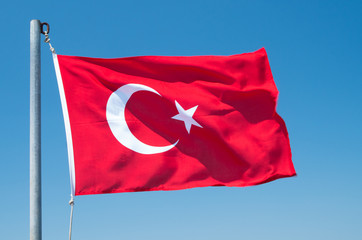 Turkish flag flutters against the blue sky.