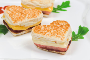 Heart shaped hot sandwiches with ham and cheese on a plate. Homemade Healthy food cooked with love. Breakfast Concept, horizontal, selective focus